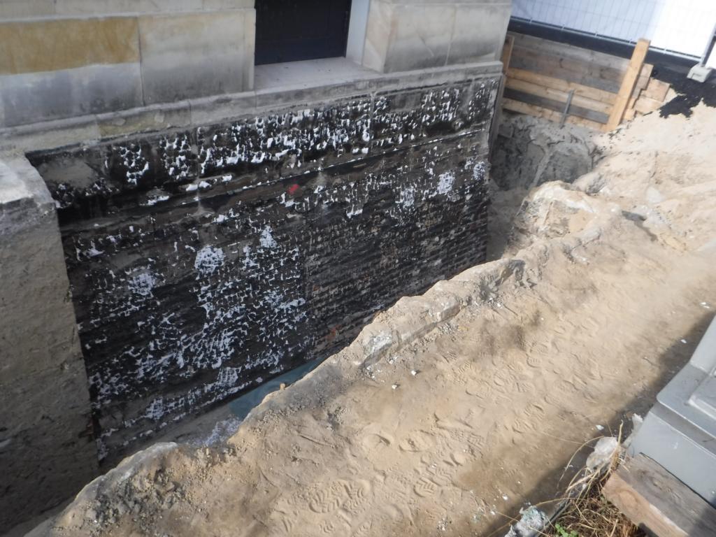 Asbesthaltiger Schwarzanstrich der Mauerwerksisolierung mit Resten der EPS-Polystrolauflage